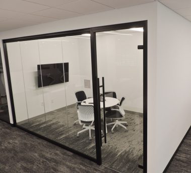 Floor-to-ceiling glass huddle room with black frame finish and frameless glass swing door #1649